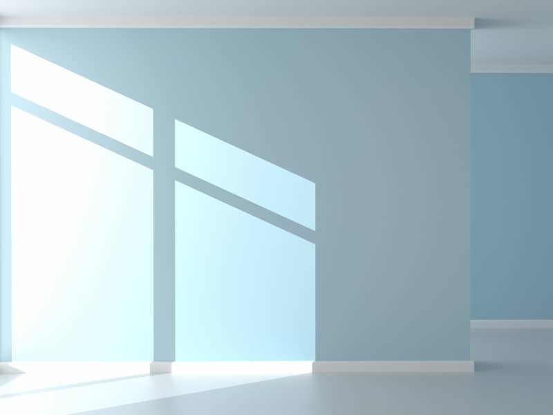 Sunlight on light blue decorative painted walls in a simple, bright room.