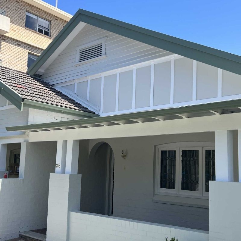 Freshly painted white weatherboard house exterior with grey trim and covered veranda completed by a professional Sydney Painter.